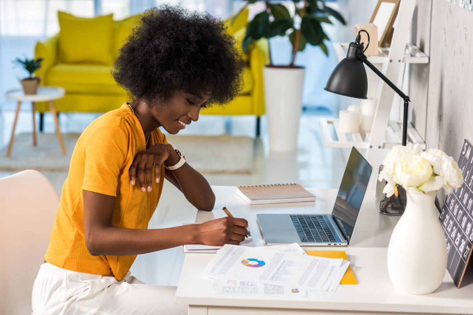 A woman sitting at her desk writing on paper.