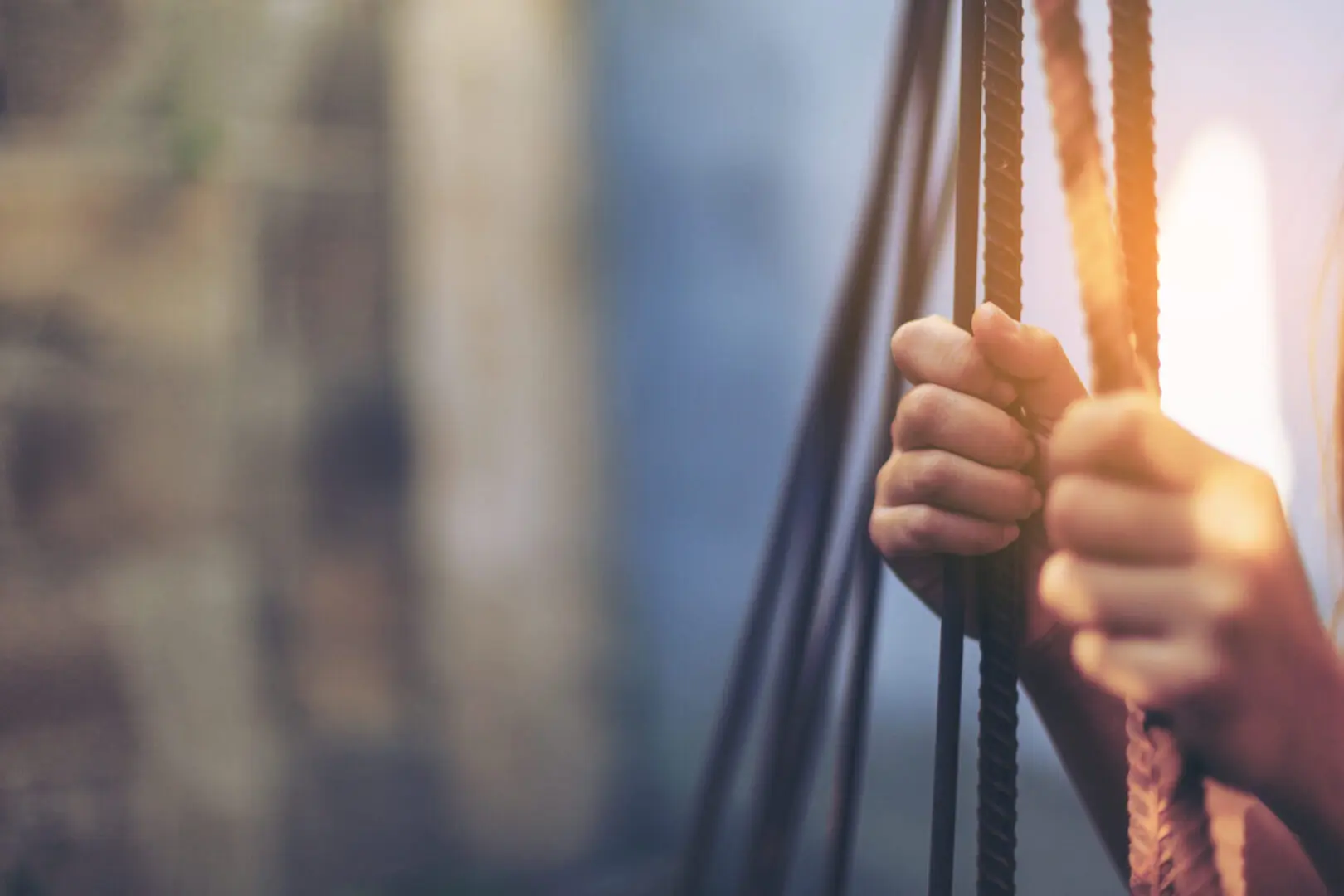 A person holding onto ropes in the sunlight.