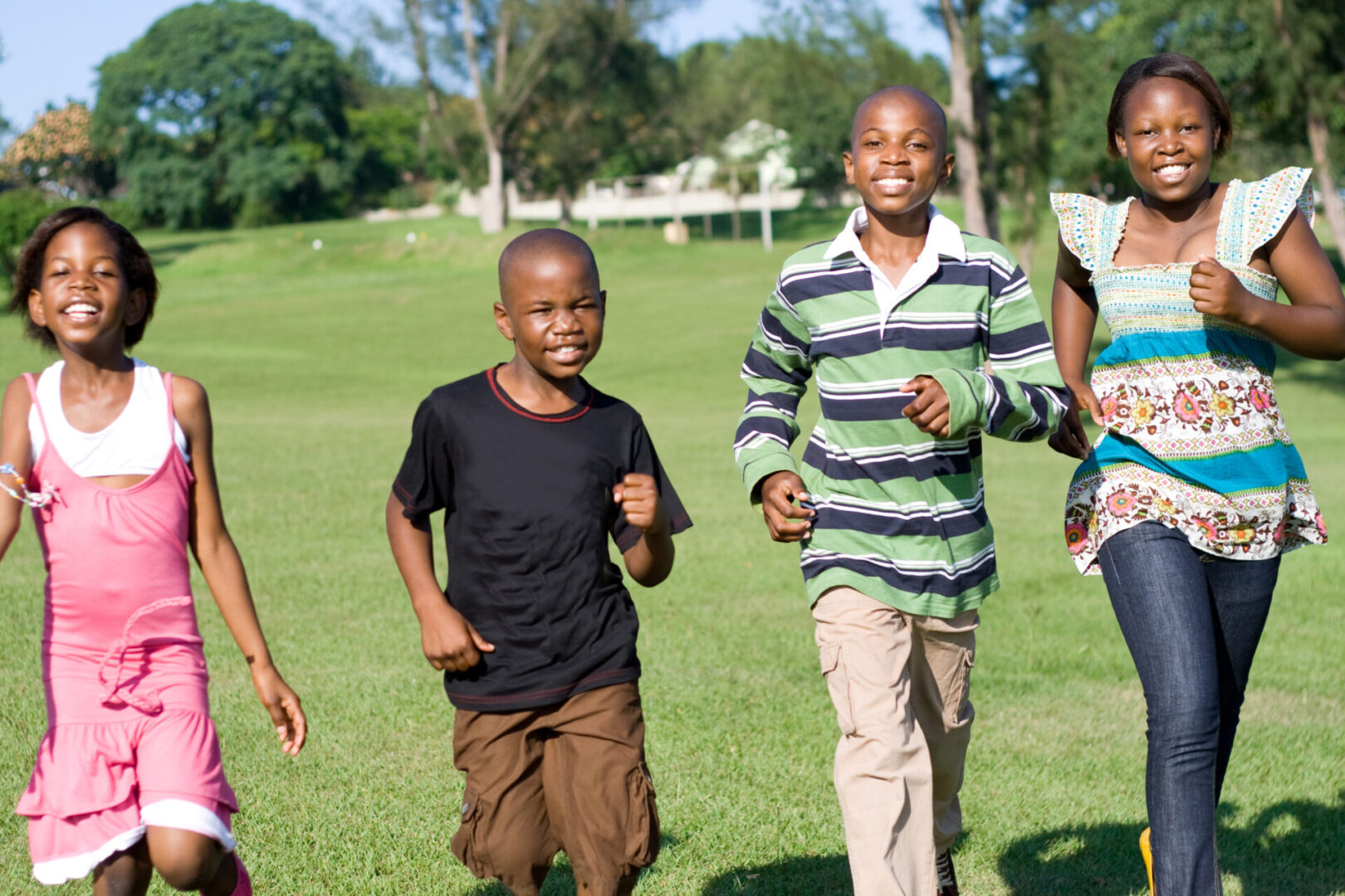 A group of kids are running in the grass.