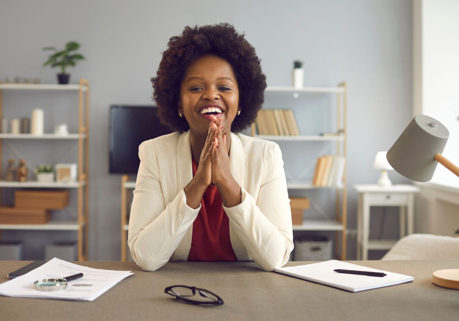 A woman sitting at her desk with her hands clasped together.